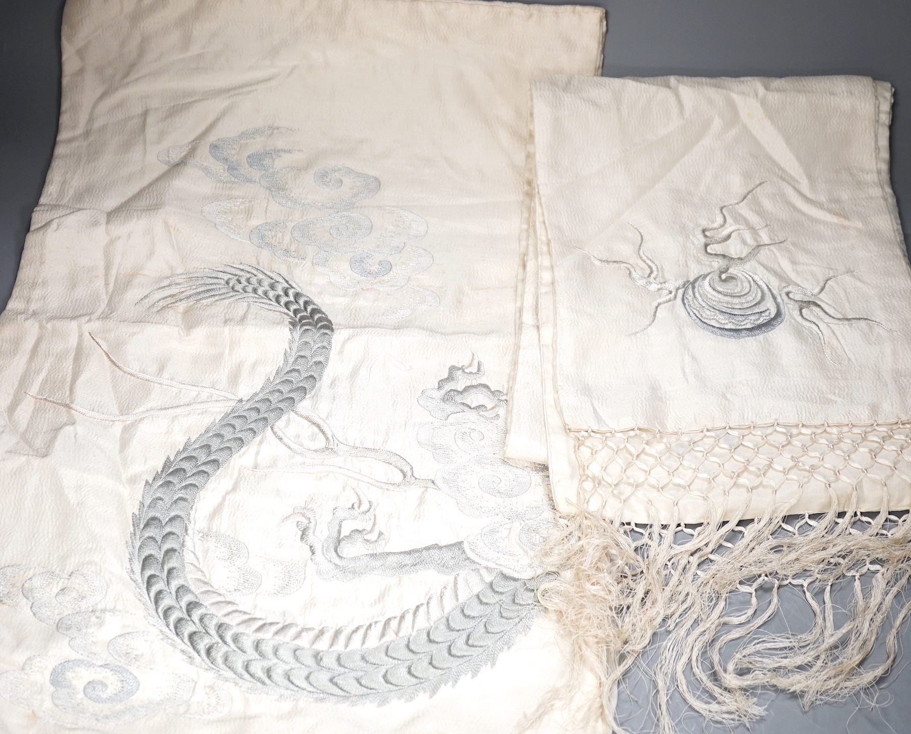 A Japanese silk kimono embroidered on mauve silk with multi-coloured butterflies and flowers, together with a cream silk unmade up kimono richly embroidered with a dragon design